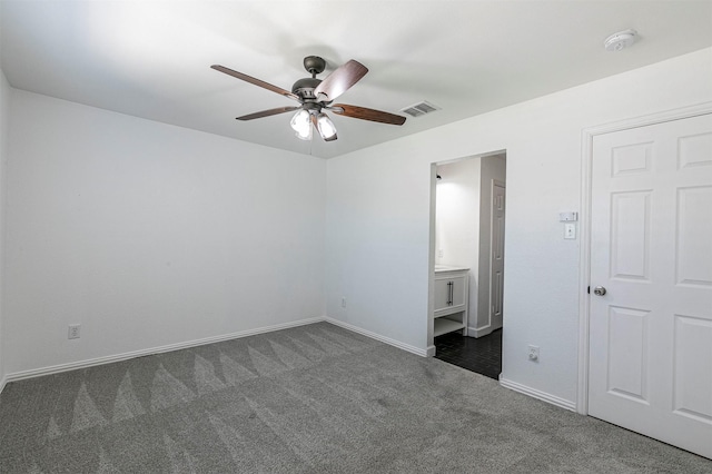 unfurnished bedroom with dark colored carpet, ceiling fan, ensuite bathroom, baseboards, and visible vents