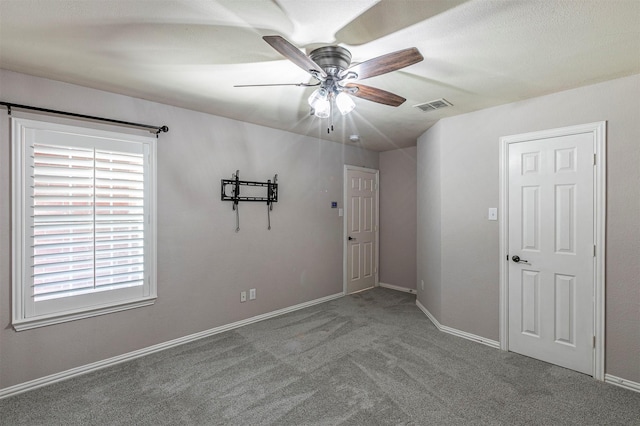 unfurnished room featuring carpet, visible vents, a ceiling fan, and baseboards