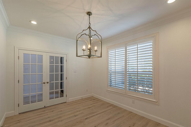 unfurnished dining area featuring a chandelier, ornamental molding, french doors, wood finished floors, and plenty of natural light