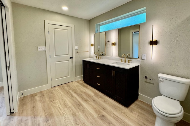 bathroom with a sink, baseboards, toilet, and wood finished floors