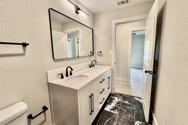 bathroom with toilet, visible vents, a sink, and marble finish floor