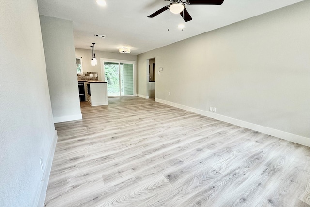 unfurnished living room featuring visible vents, a ceiling fan, light wood-style flooring, and baseboards