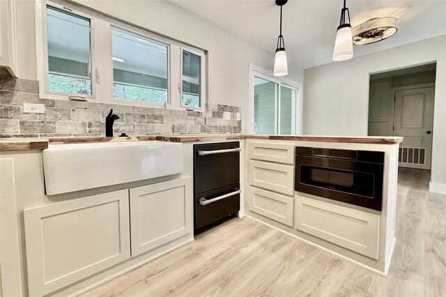 kitchen with visible vents, pendant lighting, butcher block countertops, high quality fridge, and light wood-style flooring