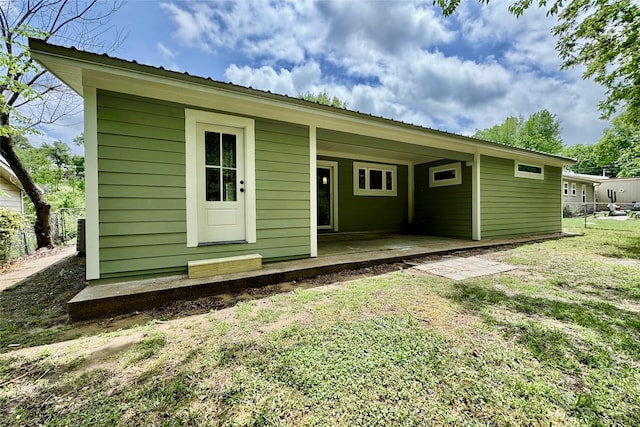 rear view of property with fence, a yard, and metal roof