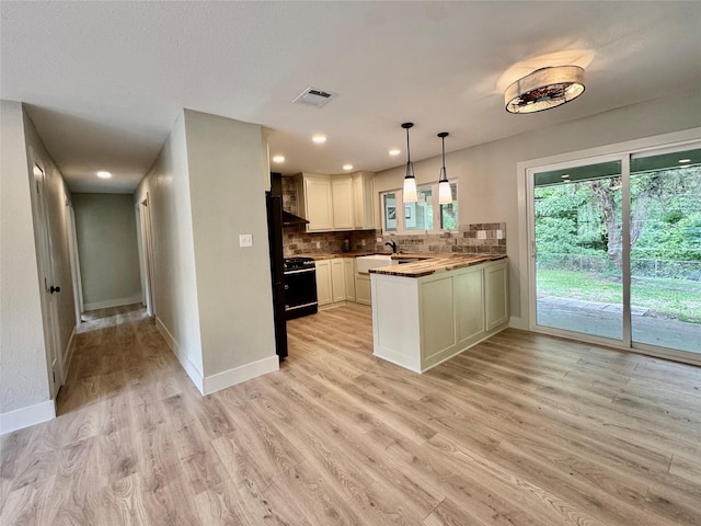 kitchen featuring decorative backsplash, a peninsula, baseboards, light wood-type flooring, and black gas range oven