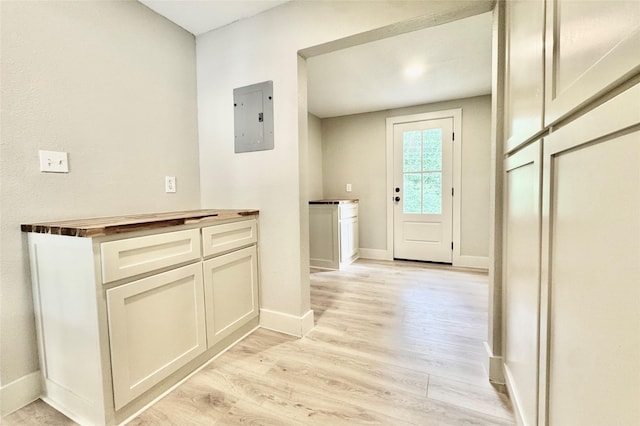 doorway featuring baseboards, light wood-type flooring, and electric panel