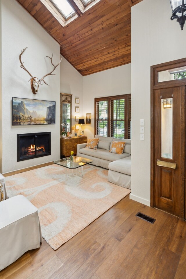 4119 Emerson Ave, University Park, TX 75205 - living room featuring a warm lit fireplace, a skylight, wood finished floors, wooden ceiling, and baseboards