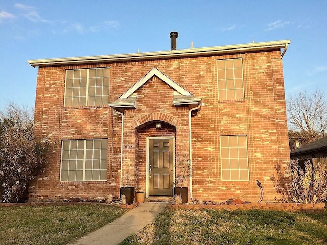 traditional home featuring brick siding and a front yard