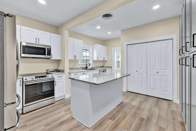 1301 N Sylvania Ave, Fort Worth, TX 76111 - kitchen featuring white cabinetry, a sink, appliances with stainless steel finishes, light stone countertops, and light wood finished floors