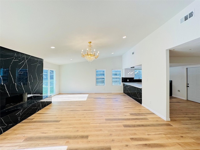 409 Bodart Ln, Fort Worth, TX 76108 - unfurnished living room featuring light wood finished floors, a chandelier, lofted ceiling, recessed lighting, and plenty of natural light