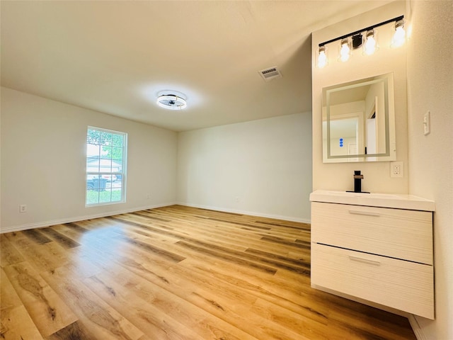 unfurnished bedroom with visible vents, light wood-type flooring, baseboards, and a sink