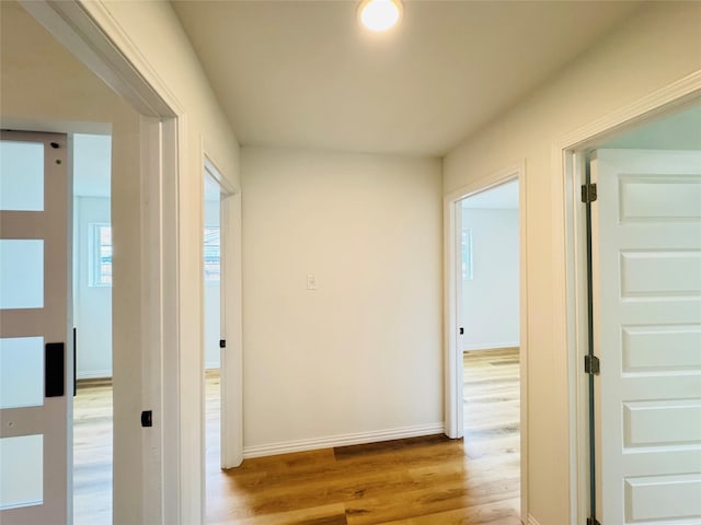 hall featuring baseboards and light wood-type flooring