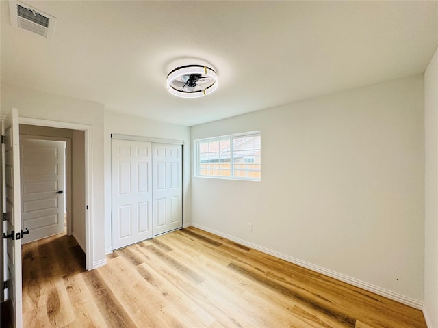 unfurnished bedroom with visible vents, a closet, baseboards, and light wood-style floors