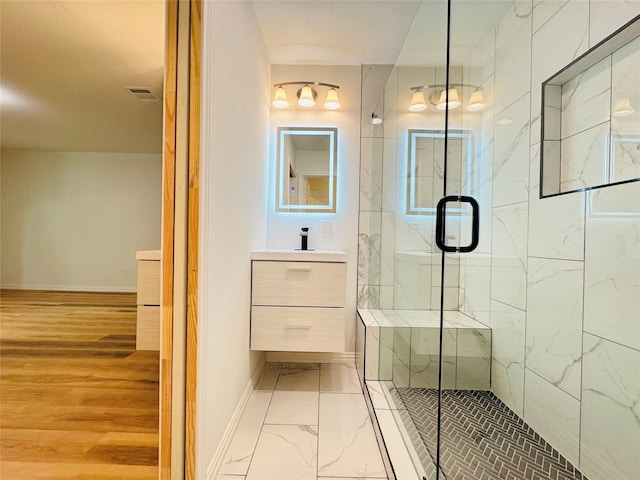 full bath featuring marble finish floor, vanity, baseboards, visible vents, and a stall shower