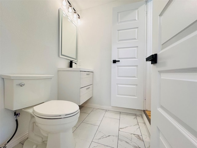 half bathroom featuring toilet, marble finish floor, vanity, and baseboards
