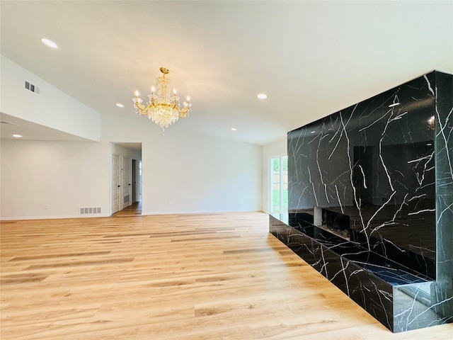 unfurnished living room featuring a notable chandelier, recessed lighting, visible vents, and wood finished floors