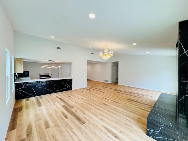 unfurnished living room featuring recessed lighting, an inviting chandelier, and light wood-style floors