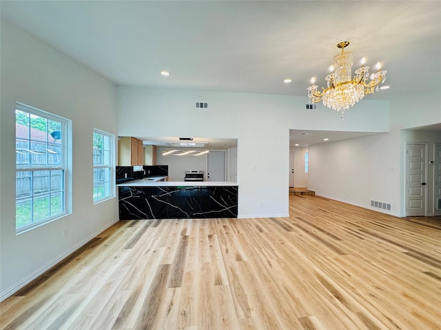 living area featuring an inviting chandelier, visible vents, light wood-type flooring, and baseboards