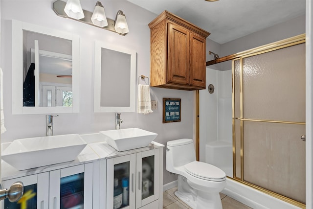 bathroom featuring tile patterned floors, a stall shower, toilet, and a sink