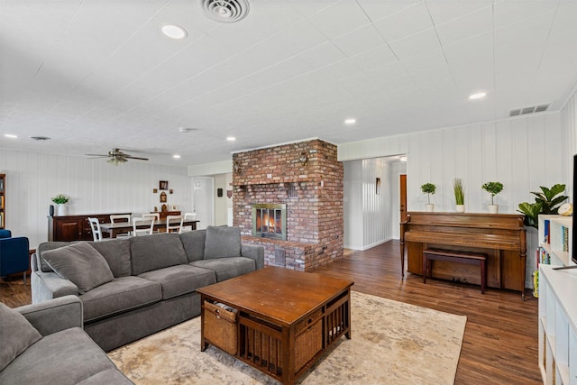 living area with a fireplace, wood finished floors, visible vents, and ceiling fan
