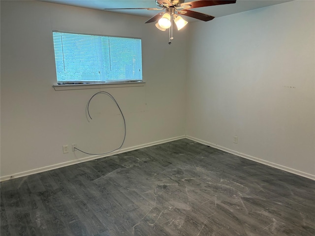 spare room featuring dark wood-style flooring, ceiling fan, and baseboards