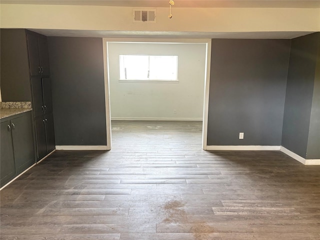 empty room featuring visible vents, wood finished floors, and baseboards