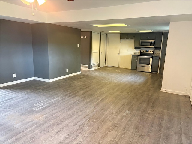 unfurnished living room featuring dark wood-type flooring, visible vents, ceiling fan, and baseboards