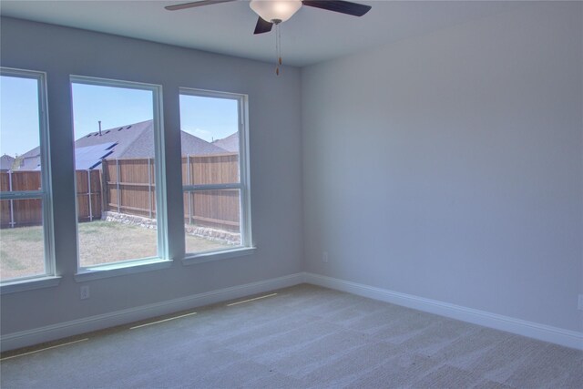 unfurnished room featuring a healthy amount of sunlight, baseboards, carpet, and a ceiling fan