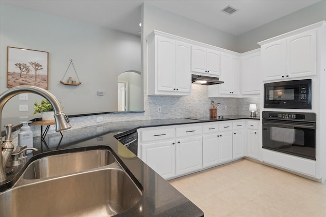 kitchen featuring tasteful backsplash, under cabinet range hood, black appliances, a sink, and visible vents