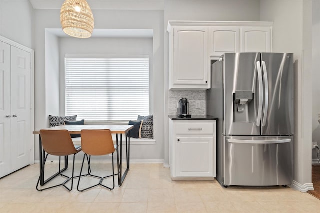 kitchen featuring tasteful backsplash, stainless steel refrigerator with ice dispenser, white cabinetry, baseboards, and dark countertops