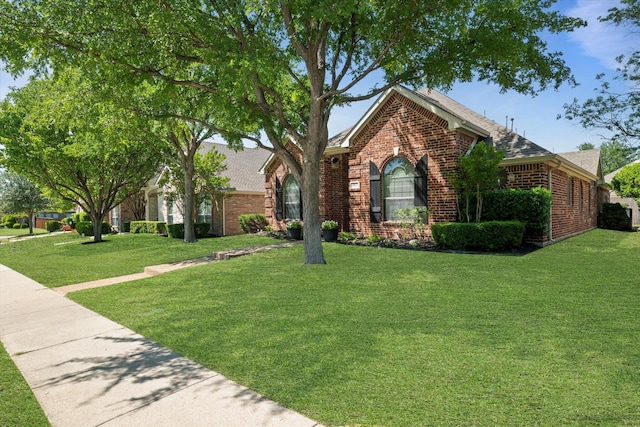 view of front of property with a front yard, roof with shingles, and brick siding