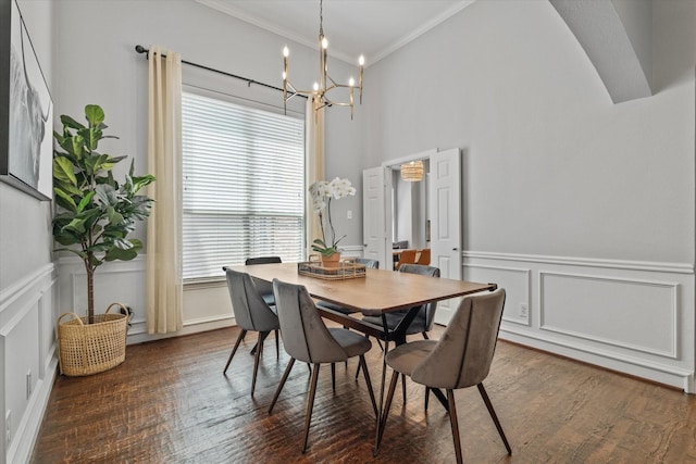 dining area with crown molding, a wainscoted wall, dark wood-style flooring, a decorative wall, and a notable chandelier