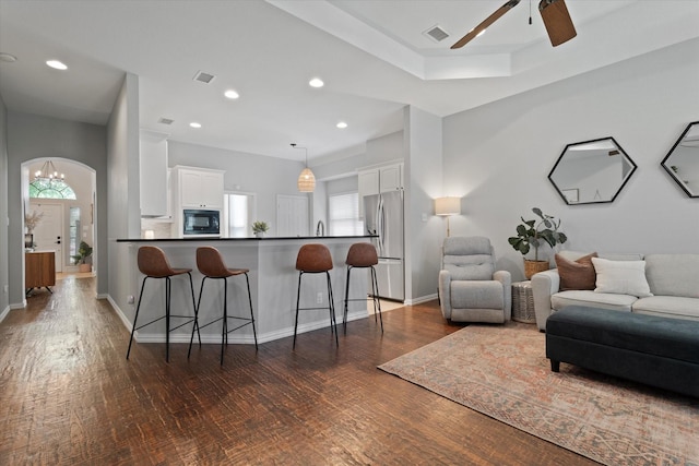 living area with dark wood-style floors, visible vents, and plenty of natural light