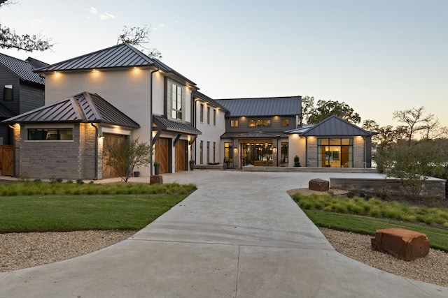 view of front facade featuring a yard, a standing seam roof, metal roof, concrete driveway, and an attached garage