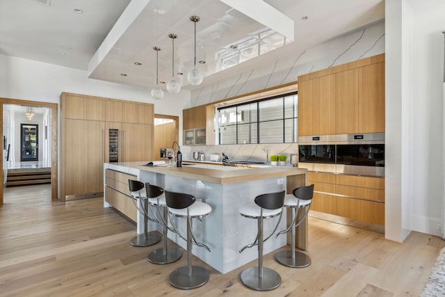kitchen featuring modern cabinets, light wood-type flooring, oven, a breakfast bar area, and a spacious island