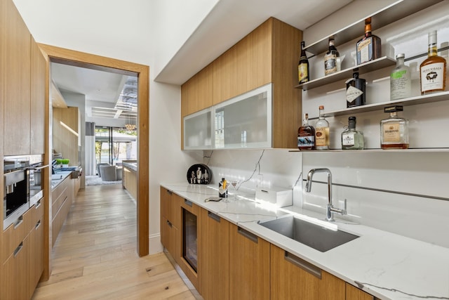 kitchen with light stone counters, modern cabinets, light wood-style flooring, and a sink