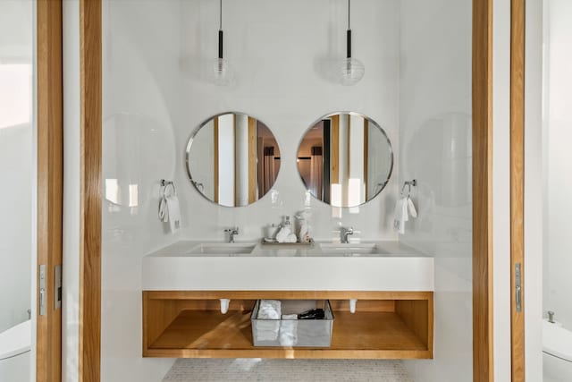 bathroom with double vanity, toilet, and a sink