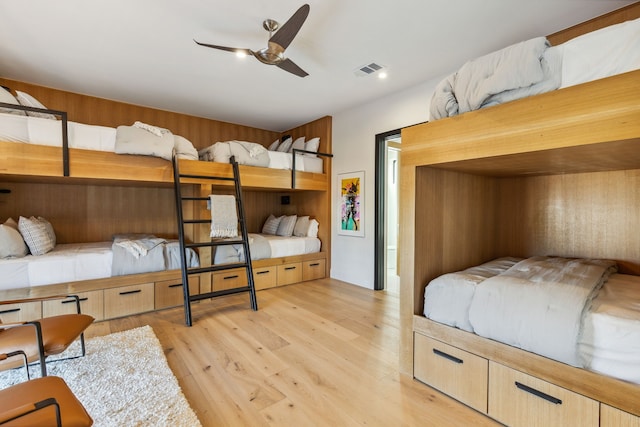 bedroom with wooden walls, visible vents, and light wood-type flooring