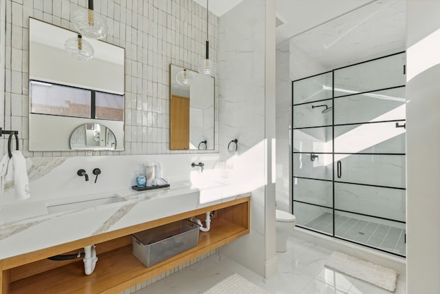 bathroom with tile walls, a shower stall, vanity, toilet, and marble finish floor