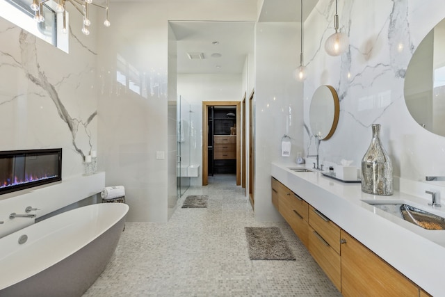 bathroom with a shower stall, a sink, double vanity, visible vents, and a freestanding bath