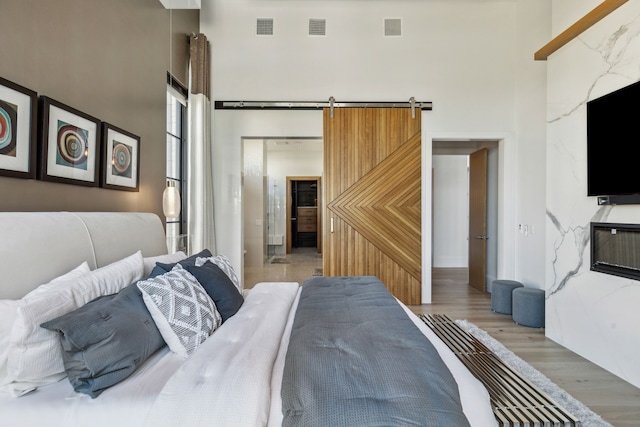 bedroom featuring a towering ceiling, visible vents, and light wood-type flooring