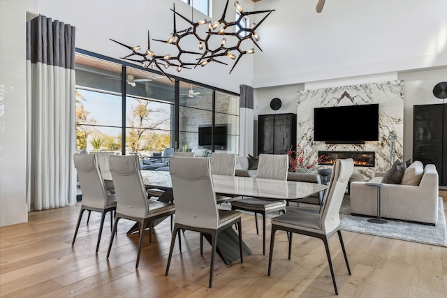 dining room with an inviting chandelier, wood finished floors, a high end fireplace, and a high ceiling