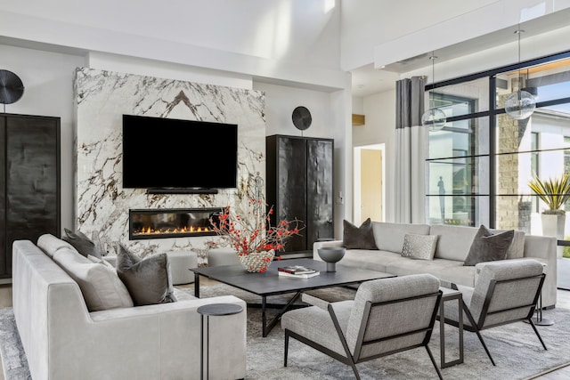 living room with a high end fireplace and a towering ceiling