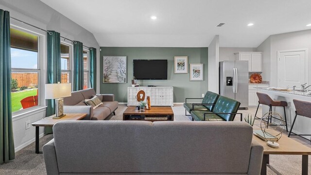 living area with lofted ceiling, light colored carpet, visible vents, baseboards, and recessed lighting