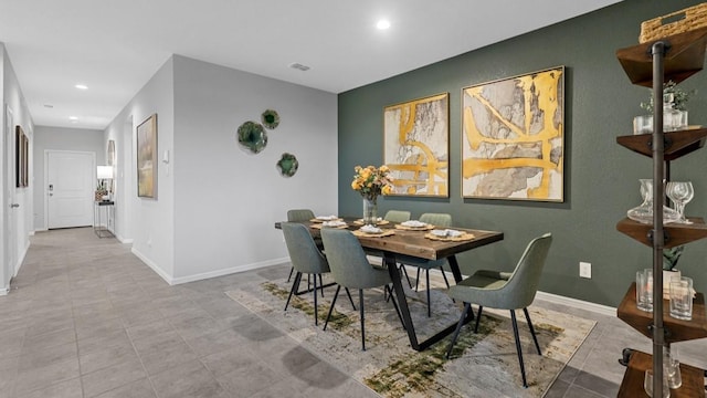 tiled dining area featuring recessed lighting, visible vents, an accent wall, and baseboards