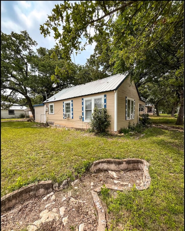 view of property exterior with metal roof and a lawn