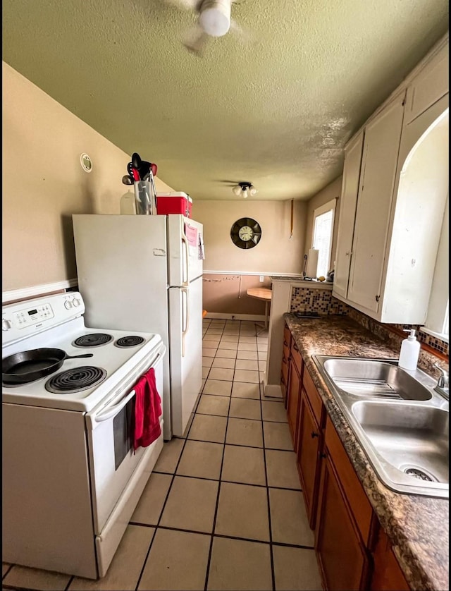 kitchen with light tile patterned floors, white electric range, dark countertops, and a sink