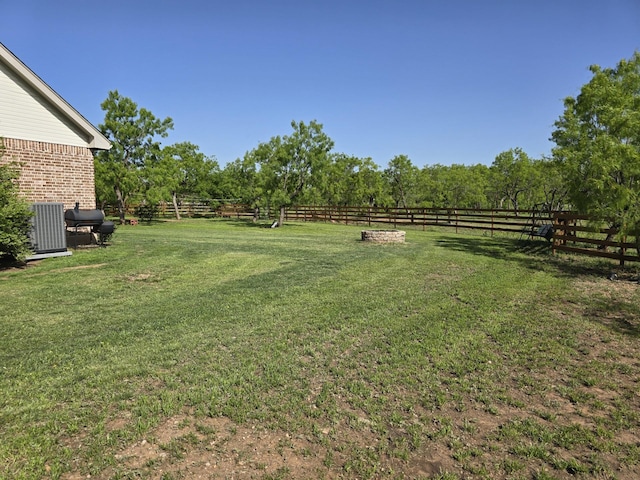 view of yard with central air condition unit, a rural view, and fence