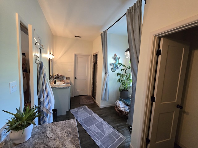 bathroom with vanity, baseboards, wood finished floors, and visible vents