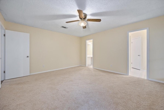 carpeted empty room featuring a textured ceiling, visible vents, ceiling fan, and baseboards